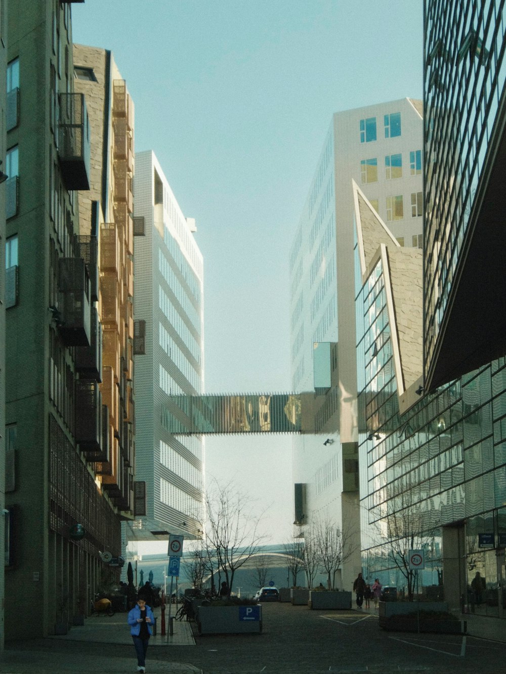 a couple of people walking down a street next to tall buildings