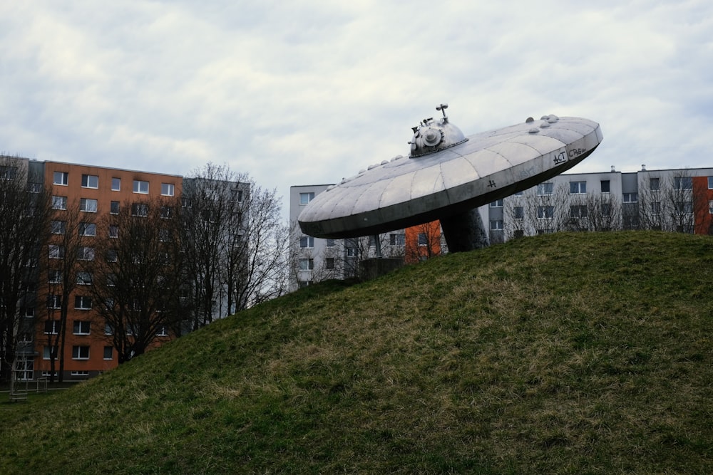 a large object sitting on top of a lush green hillside