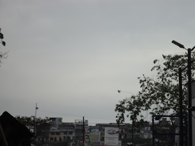 A cloudy sky with silhouettes of buildings and trees in the foreground. The scene includes a streetlamp and various signs, one of which reads 'Club Marlin's Sevilla'. The atmosphere appears overcast and muted.