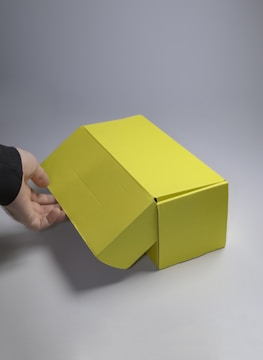 Hands delicately opening a modern product box against a minimalist background with soft natural lighting.