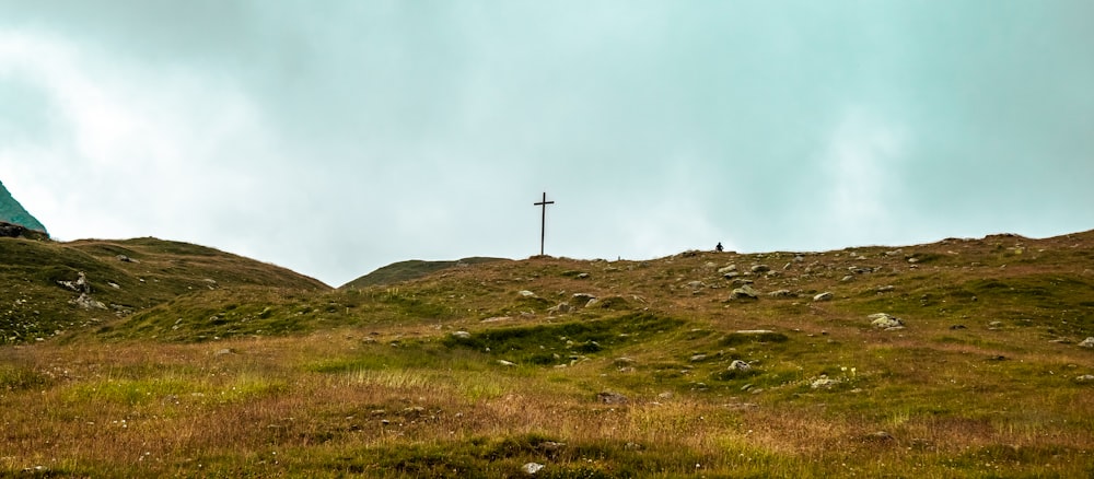 a grassy hill with a cross on top of it