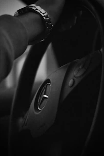 An elegant wristwatch resting on a leather racing glove beside a classic steering wheel