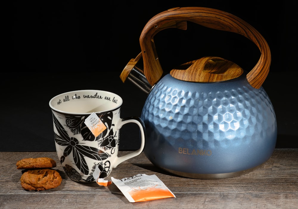 a tea kettle next to a mug and cookies