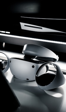 A sleek, futuristic workspace with neon blue and purple lighting highlighting a VR headset and 3D modeling screens.