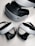 A virtual reality headset and two controllers are neatly arranged on a surface. The headset is predominantly black and white, featuring a sleek design with buttons on the side. The controllers are streamlined with curved grips and feature various buttons on the top side. They are positioned in front of the headset, highlighting their ergonomic shape.