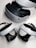 A virtual reality headset and two controllers are neatly arranged on a surface. The headset is predominantly black and white, featuring a sleek design with buttons on the side. The controllers are streamlined with curved grips and feature various buttons on the top side. They are positioned in front of the headset, highlighting their ergonomic shape.