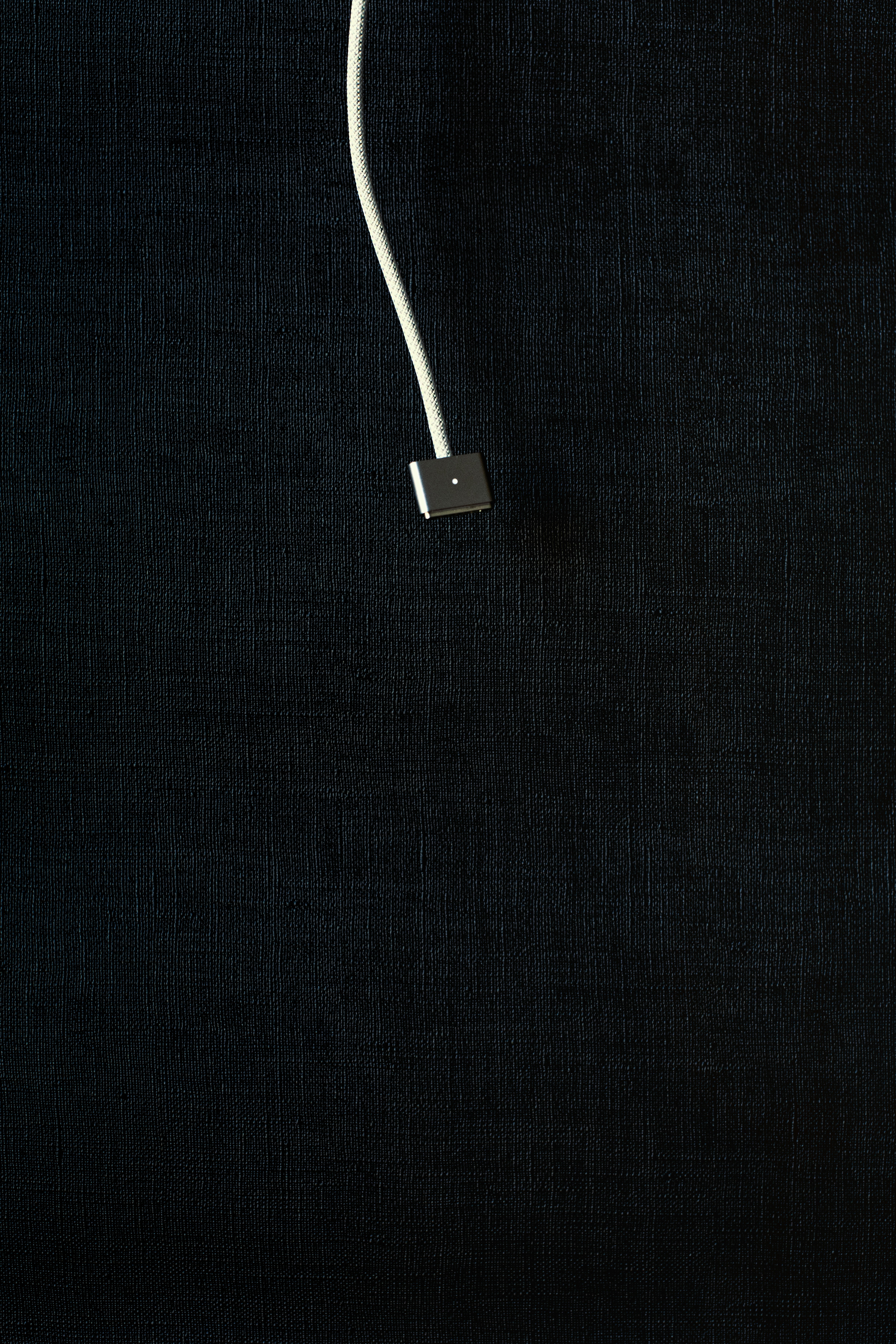 a white cord connected to a black wall