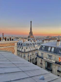 A romantic view of the Eiffel Tower at sunset with warm orange and pink hues.