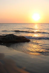the sun is setting over the water at the beach