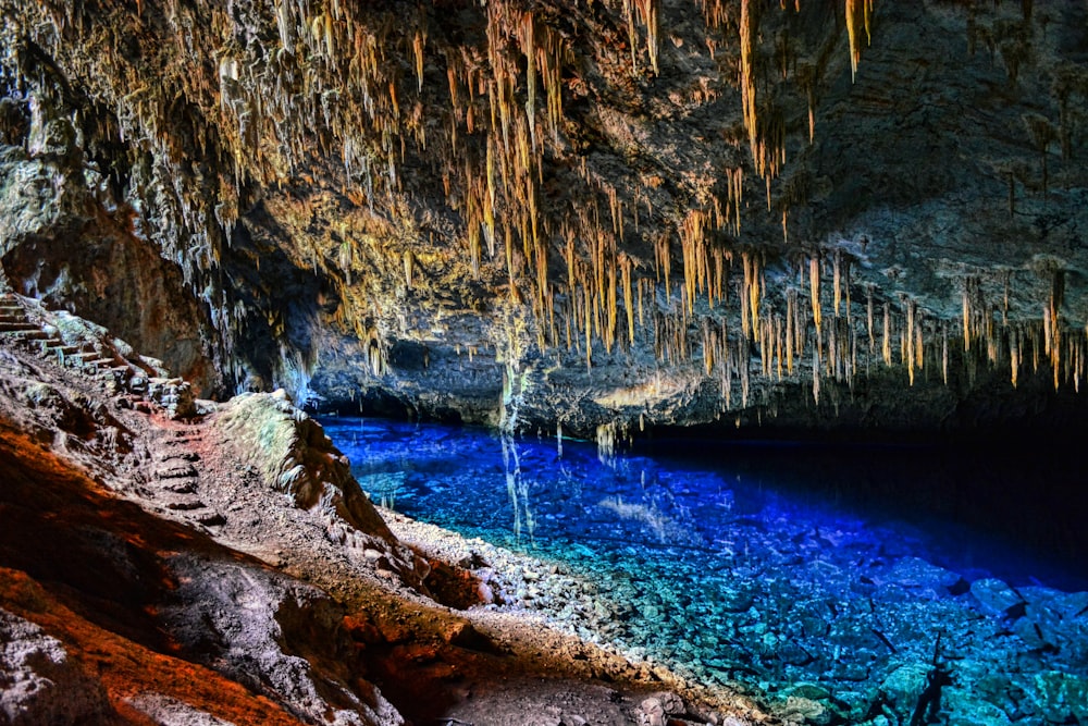 a cave filled with blue water and lots of ice hanging from the ceiling