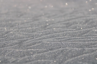A close-up of sparkling white quartz sand grains under natural sunlight.