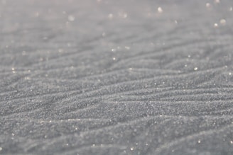 A close-up of sparkling white quartz sand grains under natural sunlight.