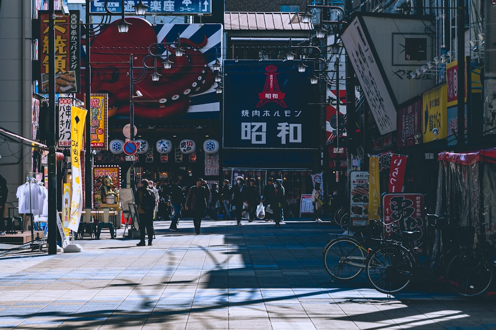 a group of people walking down a street next to tall buildings