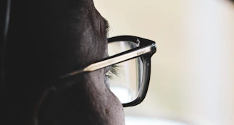 Close-up of a person wearing sleek, modern eyeglasses with a soft background.