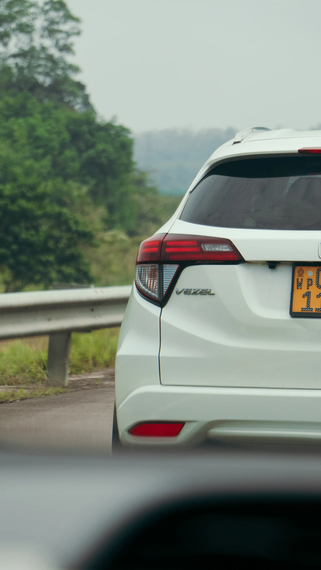 a white car driving down a road next to a forest