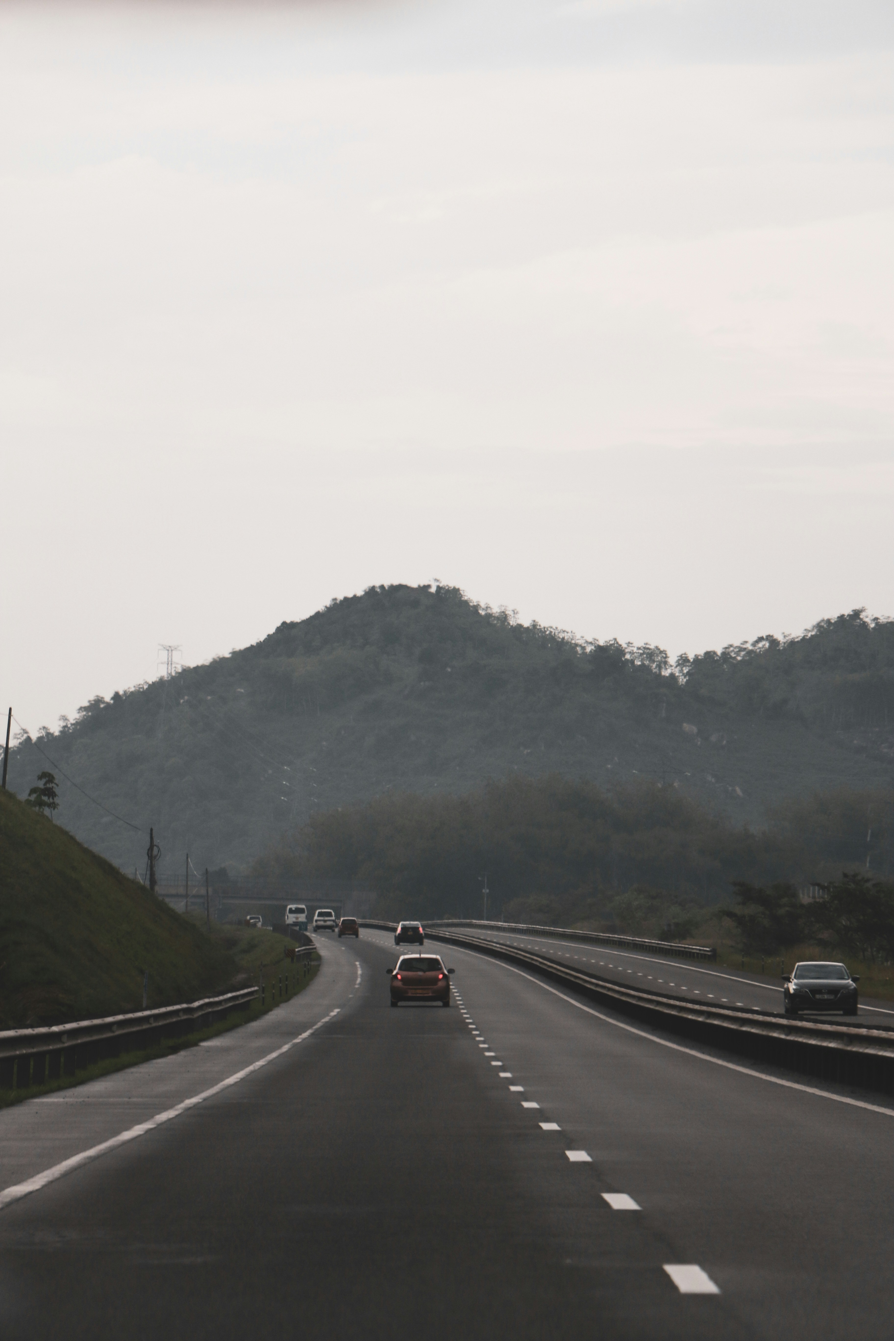 two cars driving down a road with a mountain in the background