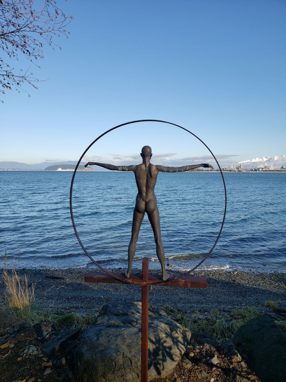 una statua di un uomo in piedi di fronte a uno specchio d'acqua