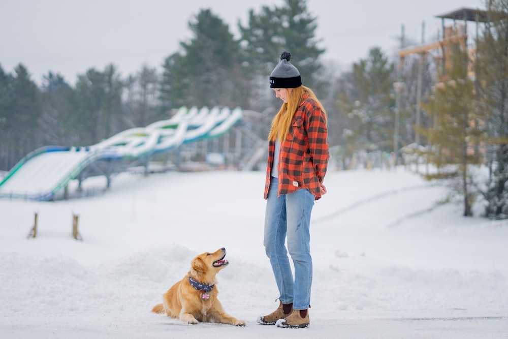 a woman standing next to a dog in the snow