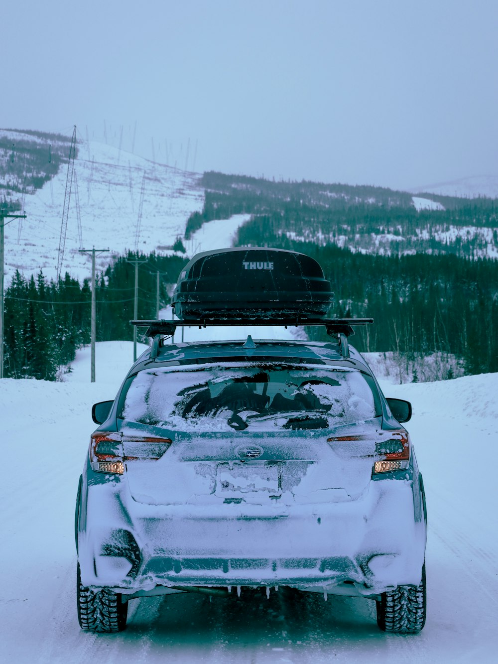 a car parked on a snowy road with a ski lift in the background