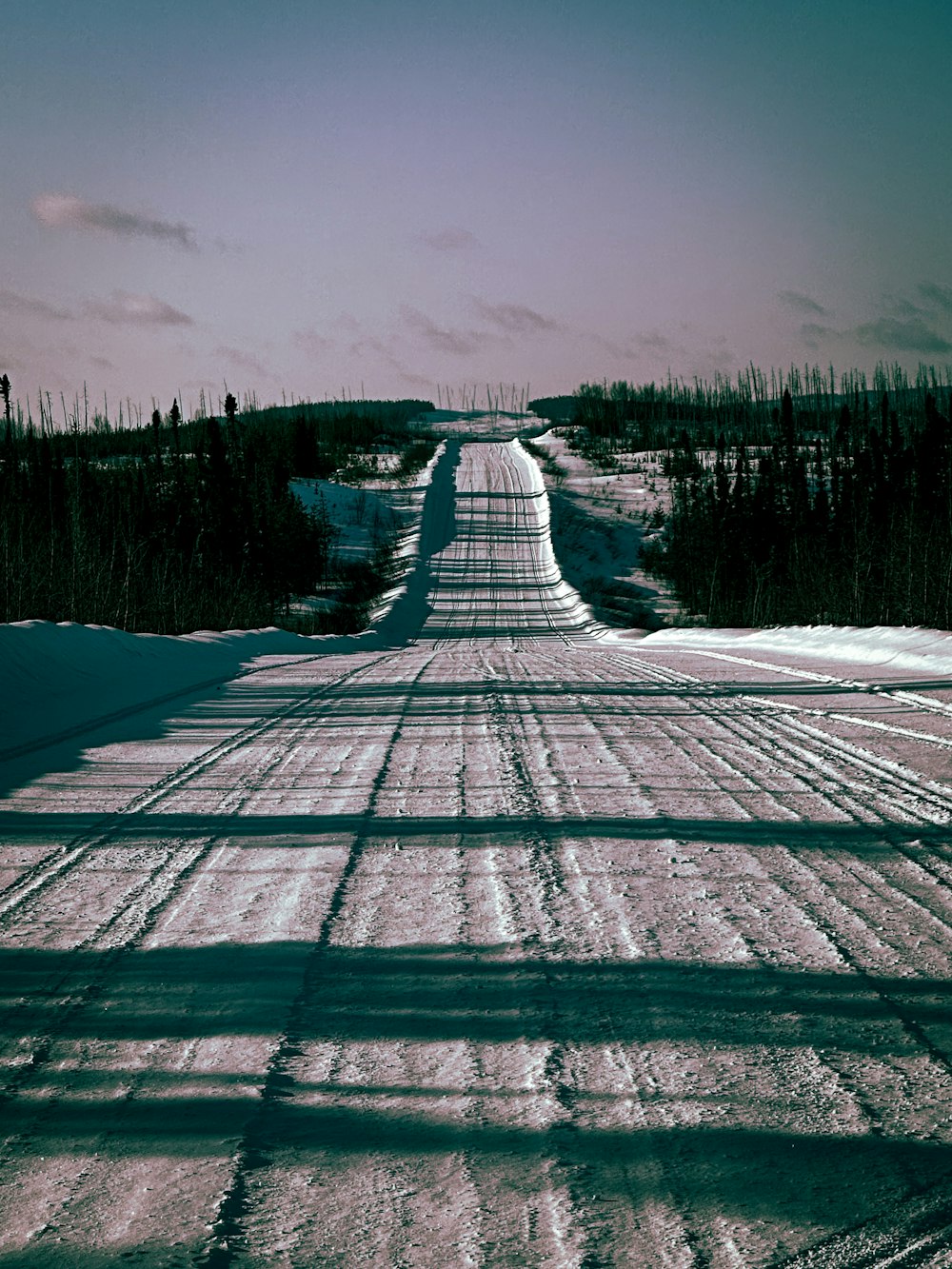 a snow covered road in the middle of a field