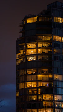 An inviting multi-family rental building bathed in warm evening light, with tenants visible through windows.