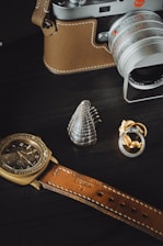 Close-up of a vintage camera and wedding rings on a minimalist wooden table.