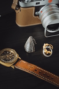 Close-up of a vintage camera and wedding rings on a minimalist wooden table.