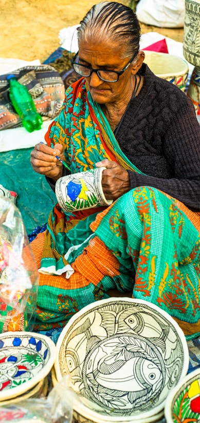 a woman sitting on the ground working on a piece of art