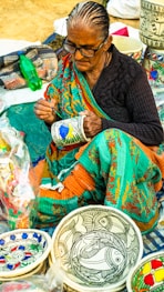a woman sitting on the ground working on a piece of art