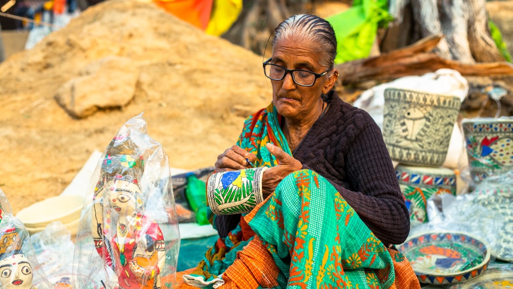 a woman sitting in front of a pile of pottery