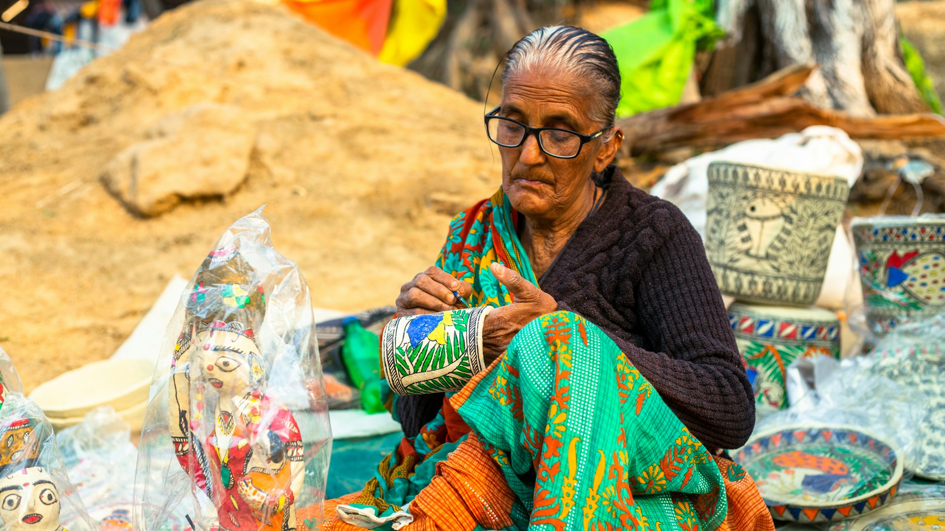 a woman sitting in front of a pile of pottery