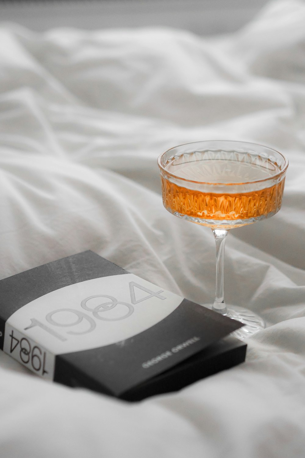 a glass of alcohol sitting on top of a bed