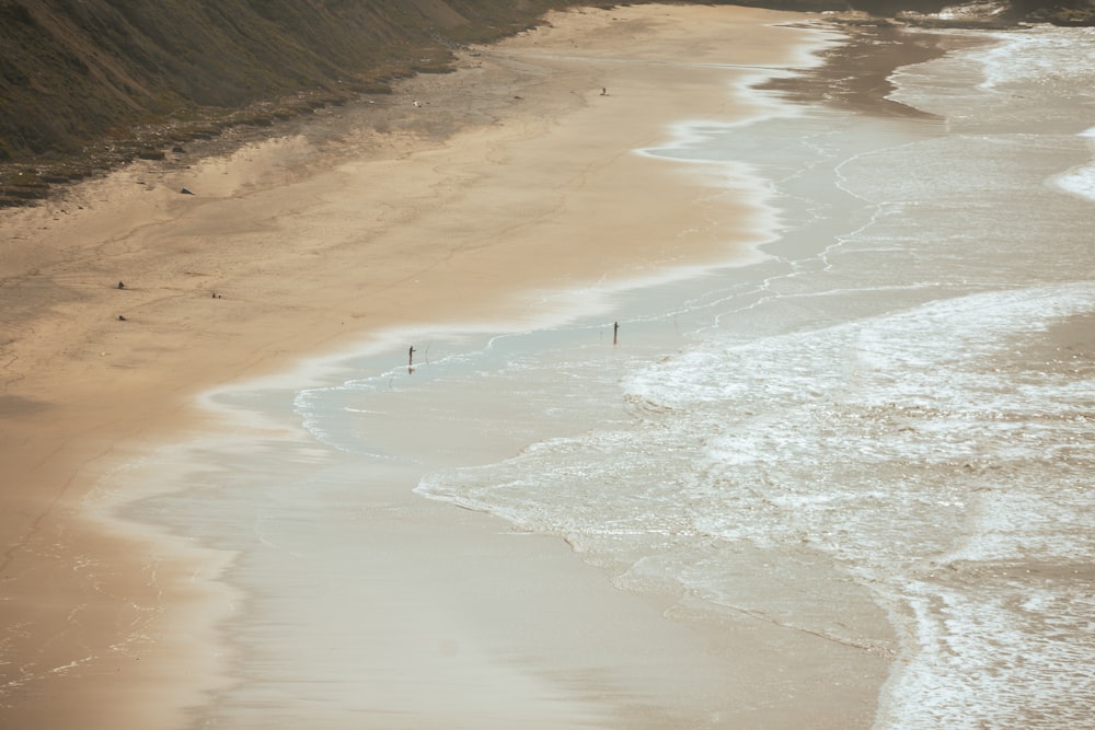 a sandy beach next to the ocean with waves coming in