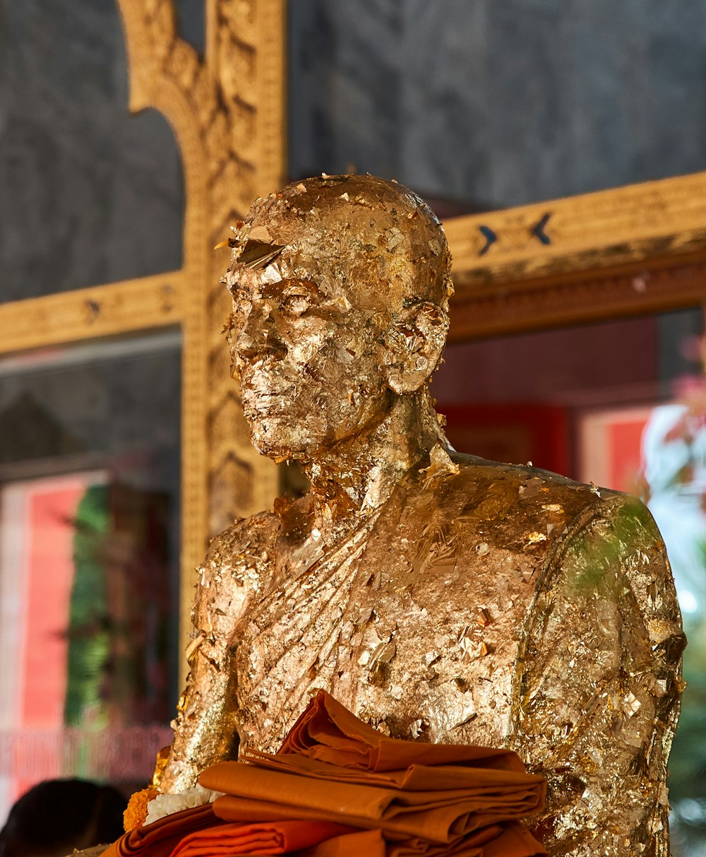 une statue dorée d’un homme tenant un tissu