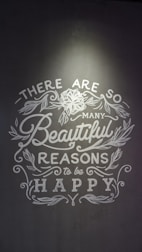 Inspirational text with floral decorations on a gray background, emphasizing positivity and happiness.