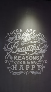 Inspirational text with floral decorations on a gray background, emphasizing positivity and happiness.
