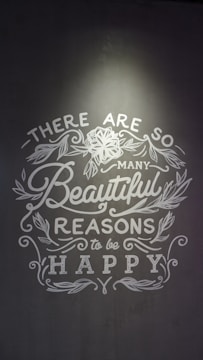 Inspirational text with floral decorations on a gray background, emphasizing positivity and happiness.
