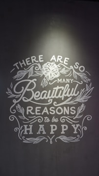 Inspirational text with floral decorations on a gray background, emphasizing positivity and happiness.