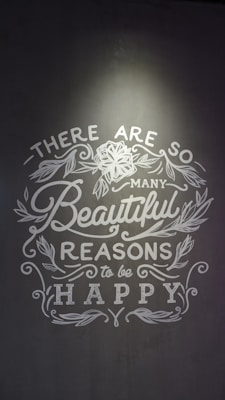 Inspirational text with floral decorations on a gray background, emphasizing positivity and happiness.