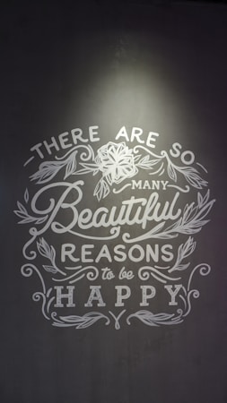 Inspirational text with floral decorations on a gray background, emphasizing positivity and happiness.