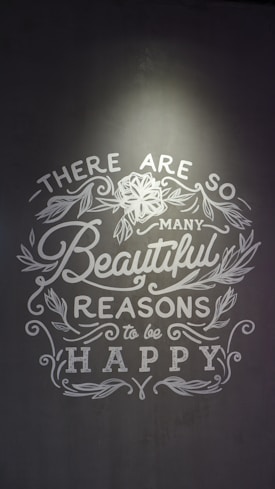 Inspirational text with floral decorations on a gray background, emphasizing positivity and happiness.