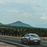 A sleek silver convertible with the top down, cruising along a scenic route.