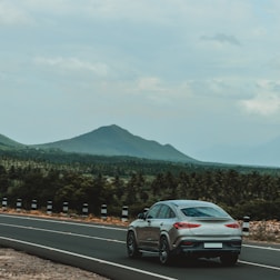 A sleek car fitted with new tires driving smoothly on a scenic road.