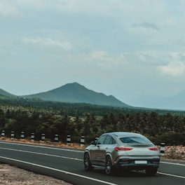 A sleek, modern car driving along a scenic Portuguese road.