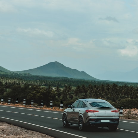 Elegant silver sedan cruising on a mountain highway with clear blue skies.