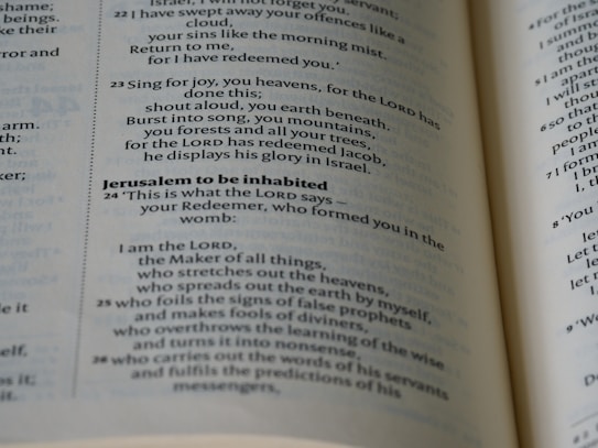 A close-up view of a page from a printed book containing religious text with verses and headings in a bold font. The text appears to be from the Bible, featuring passages that reference themes of redemption and divine actions.