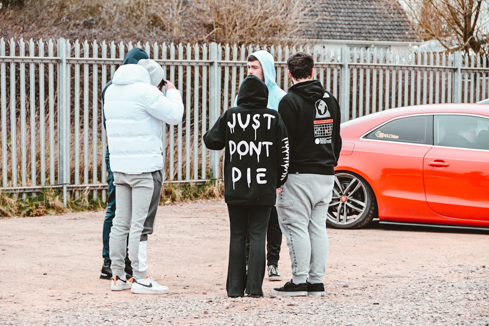 a group of people standing in front of a red car