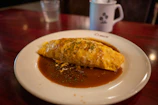 A beautifully plated omelette with fresh herbs and a side of toasted bread on a rustic wooden table.