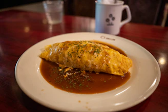 A close-up of a fluffy omelette garnished with fresh herbs on a white plate.
