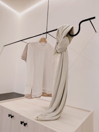 A trendy t-shirt yarn bag hanging on a minimalist hook against a pastel wall.